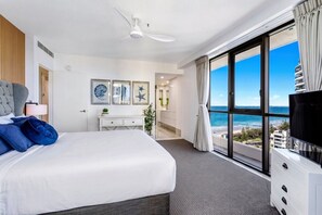 A hotel room with a large bed, a desk, a TV, and a balcony with a view of the ocean. - Surf & Sunrise Beachfront Hideaway by Inn Paradise (Surfers Paradise)