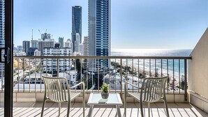 A balcony with two chairs, a small table, and a potted plant. - Surf & Sunrise Beachfront Hideaway by Inn Paradise (Surfers Paradise)