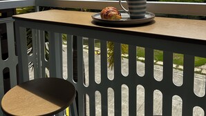 A balcony with a table, a chair, a plate with a croissant, and a mug.