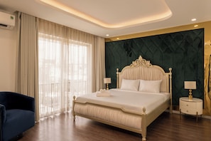 A hotel room with a large bed, a bedside table, a chair, and a view of the outdoors through the window. - D2 Center Pool Villa with 6 bedrooms (An Khanh Ward)