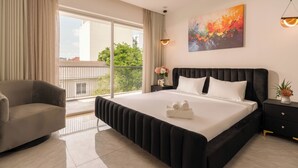 Une chambre d’hôtel moderne dotée d’un grand lit, d’un canapé, d’une table de chevet et d’un balcon avec vue.