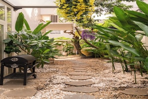 A garden pathway with stepping stones, a barbecue grill, and various plants. - D2 Center Pool Villa with 6 bedrooms (An Khanh Ward)