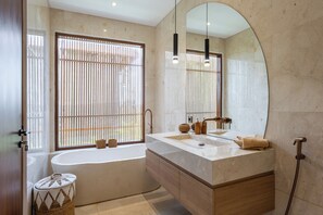 A modern bathroom with a bathtub, a large mirror, and a vanity with a sink. - Villa Albizia - 2BR private pool villa near Canggu (Mengwi)