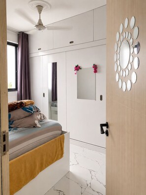 A bedroom with a bed, a ceiling fan, a window with curtains, a mirror, and a wall with circular mirrors. - 2-bedroom apartment in adorable Male City with AC comfort (Male City)