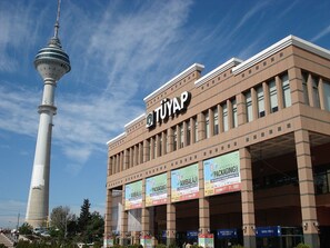 Ein Gebäude mit einem markanten Turm, einer Beschilderung mit dem Schriftzug 'TIVAP' und mehreren Bannern, die Veranstaltungen bewerben.