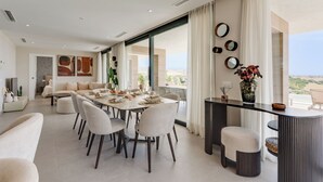 Un espace repas moderne, doté d’une grande table, de chaises et offrant une vue sur le paysage.