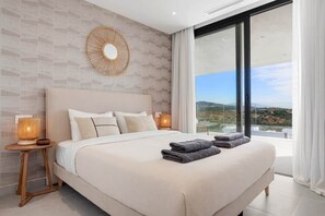Ett modernt hotellrum med en stor säng, utsikt över landskapet och en dekorativ väggdekoration.