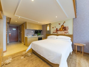 A hotel room with a bed, a small kitchenette, and a mural on the wall.