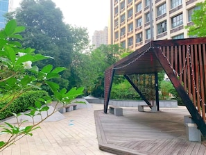 A wooden pavilion with benches, surrounded by greenery and a tiled walkway. - Vienna International Hotel (Guangzhou)