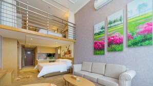 Habitación de hotel con cama en literas, sofá, una mesa de centro y zona de cocina.