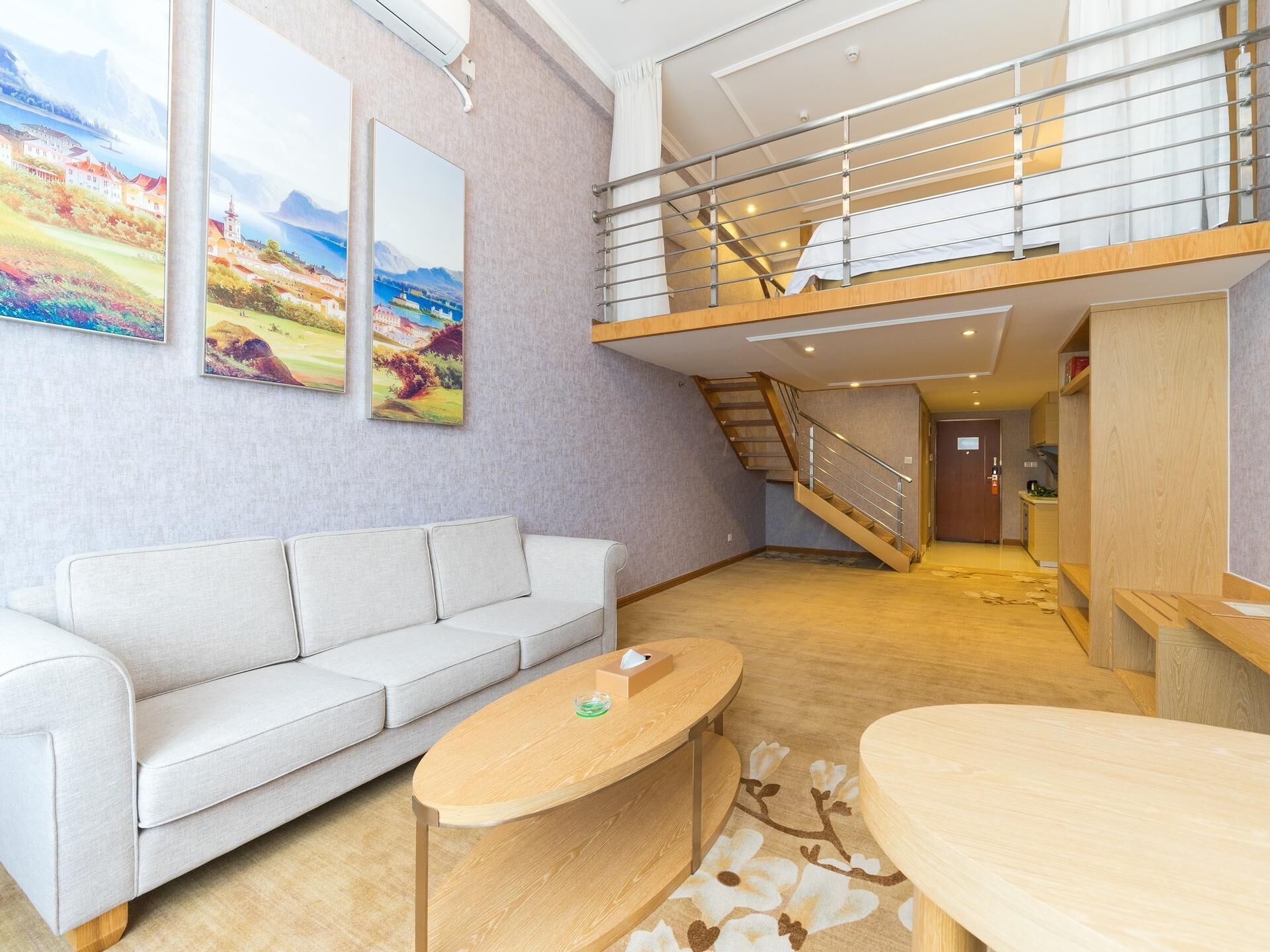 Un interior moderno con un sofá, una mesa de centro, una escalera y vistas de un paisaje pintoresco a través de grandes ventanales.