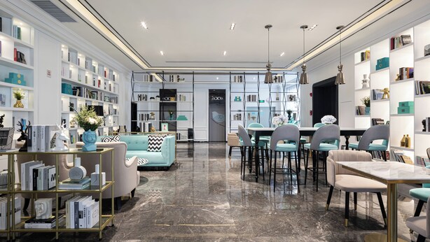 A modern interior with a central dining area, bookshelves, and a sofa. - XANA International Hotel Baiyun (Guangzhou)