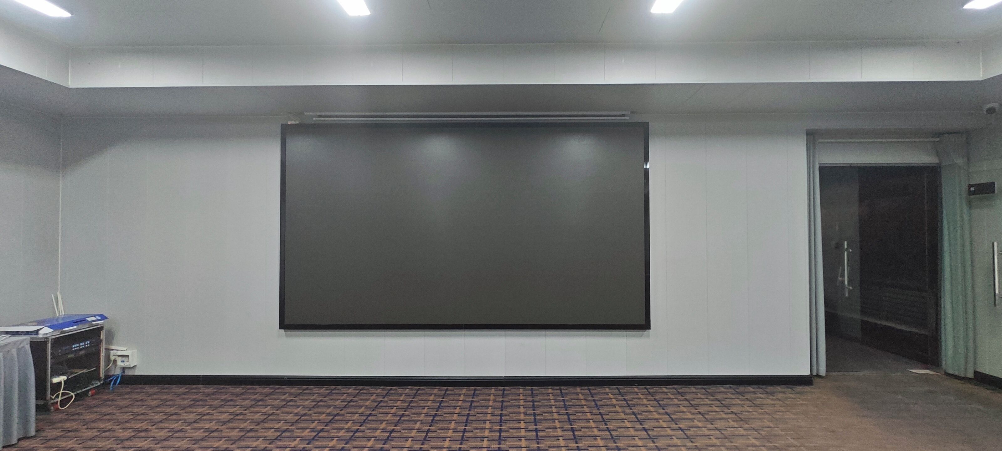 Un salón de conferencias con una pantalla de proyección grande, una puerta y un suelo de baldosas.