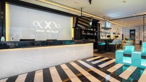 A hotel reception area with a marble counter, a reception desk, and a bar area with shelves of bottles. - XANA International Hotel Baiyun (Guangzhou)