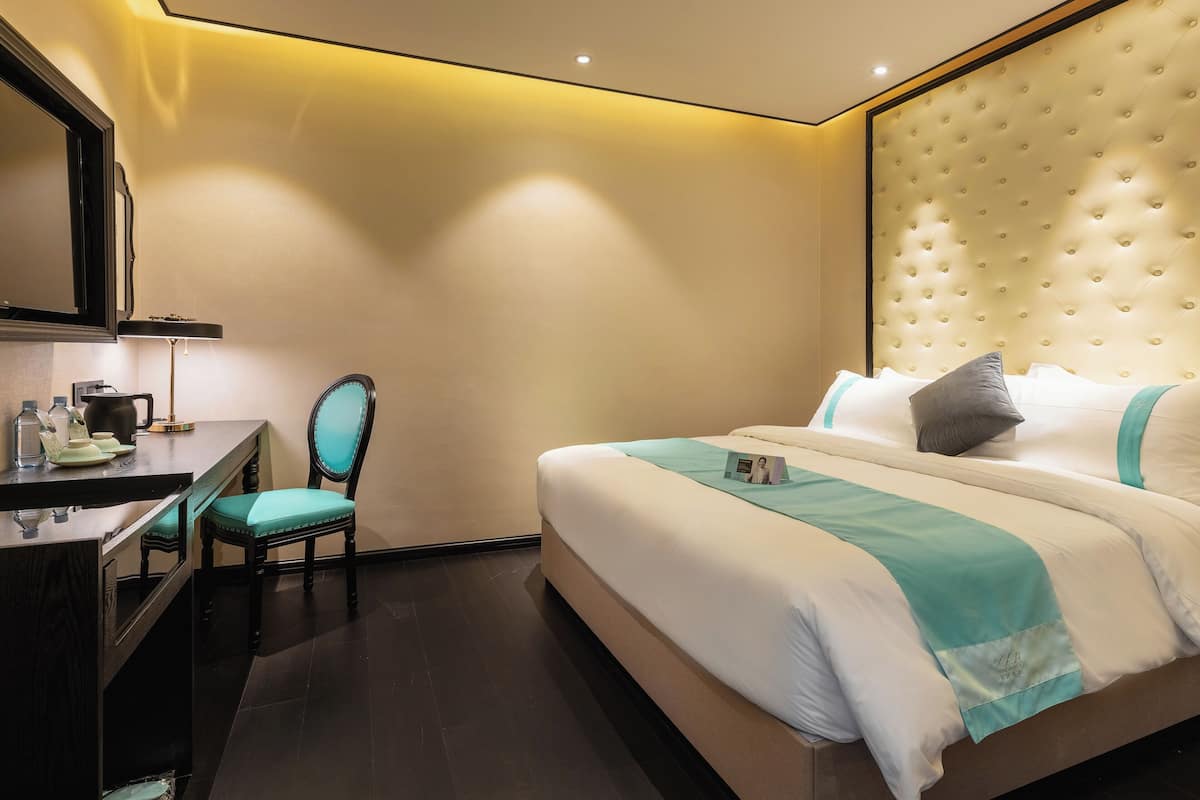 Una habitación de hotel con cama, escritorio, silla y espejo.