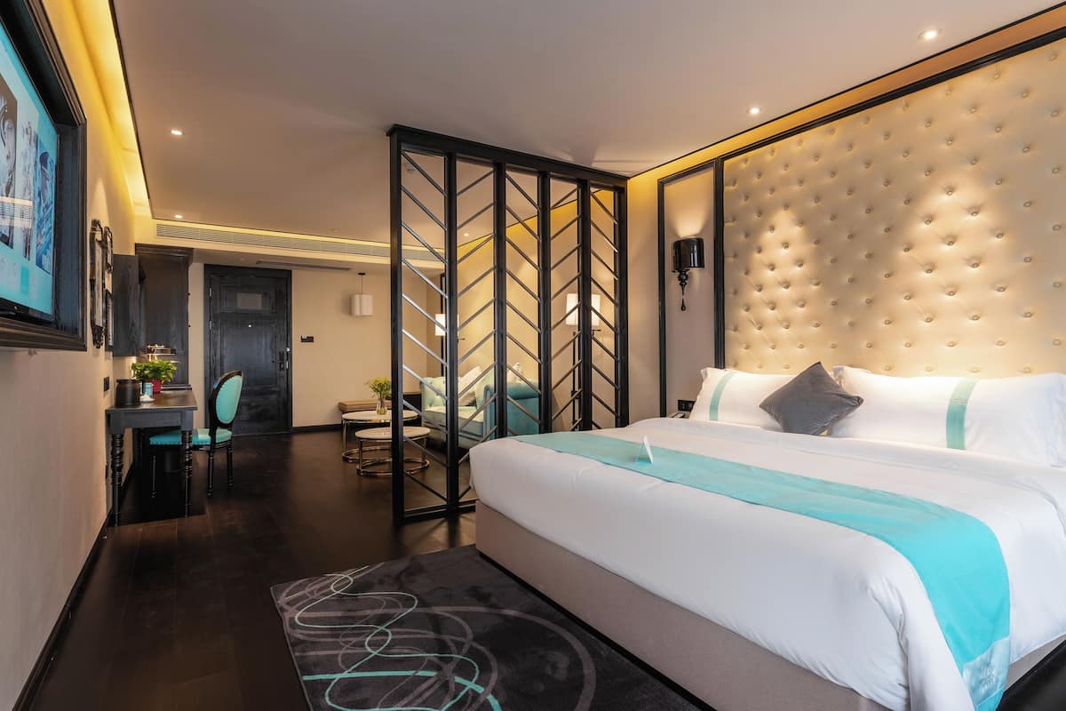 Una habitación de hotel moderna con una cama grande, un escritorio, una silla y un panel decorativo en la pared.