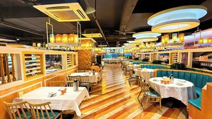 A restaurant with wooden flooring, tables with white tablecloths, and blue cushioned booths. - XANA International Hotel Baiyun (Guangzhou)