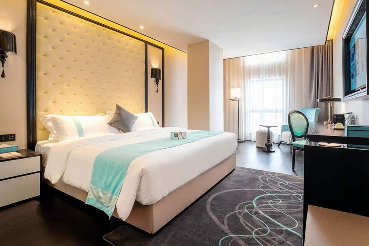 Una habitación de hotel moderna con una cama grande, mesitas de noche, un escritorio y una silla.