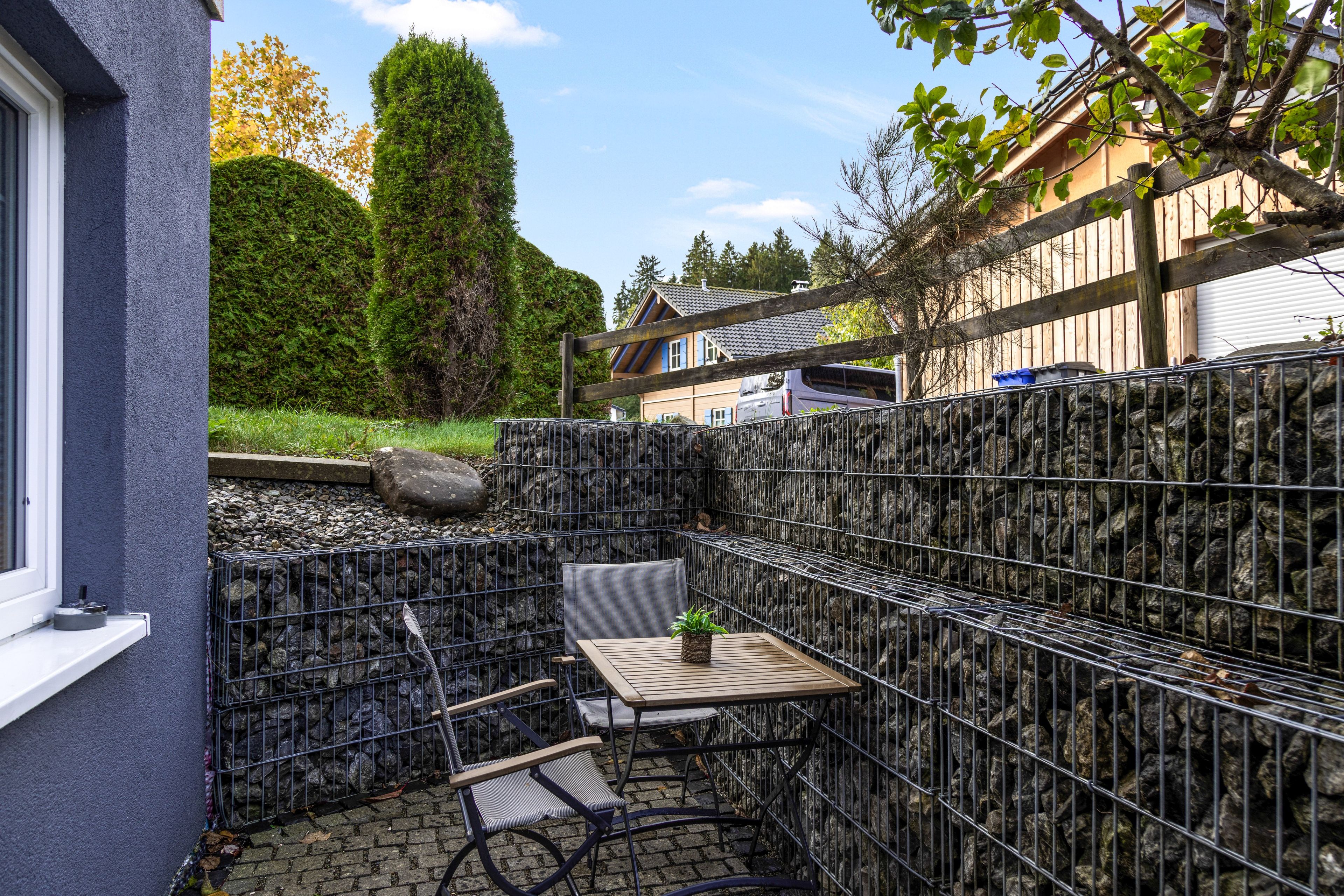 Eine Terrasse mit Tisch und Stühlen, umgeben von einem Metallzaun.