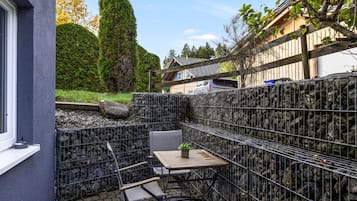 Eine Terrasse mit Tisch und Stühlen, umgeben von einem Metallzaun.