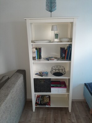 Ein weißes Bücherregal mit Büchern, einer Lampe und verschiedenen Dekorationselementen.