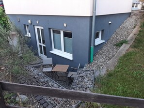 Asuinrakennuksessa on harmaa julkisivu, useita ikkunoita ja selvästi näkyvä portaikko, joka johtaa sisäänkäyntiin.
