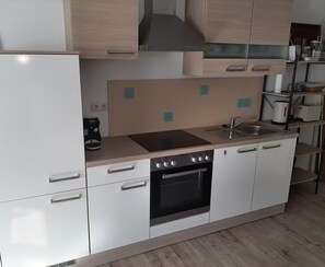 Una cocina compacta con refrigerador, estufa, horno y pileta.