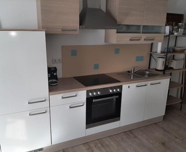 A compact kitchen with a refrigerator, stove, oven, and sink.