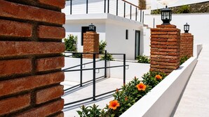 A modern building with white walls, brick accents, and a metal railing.