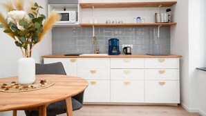 A kitchen with white cabinets, a microwave, a coffee maker, and a vase with dried flowers on the counter. - Faraway Homes Studio Semmering #303 (Spital am Semmering)