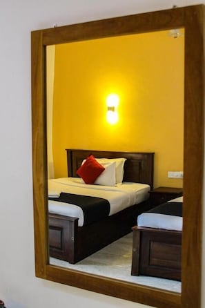 A bed with a wooden headboard, a bedside table, and a nightstand in a room with yellow walls. - Heavens Gate Ella (Ella)