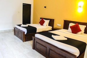 Two twin beds with wooden headboards, white linens, and red pillows in a room with a tiled floor and a door in the background. - Heavens Gate Ella (Ella)