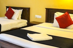 Two beds with white linens and red pillows, a folded white towel on the bed, and a wooden nightstand between them. - Heavens Gate Ella (Ella)