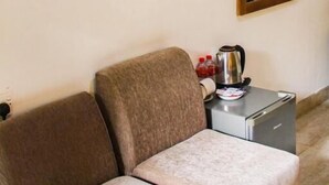 A room with a flat-screen TV mounted on the wall, a wooden-framed mirror, a sofa, a small table with a kettle, and a coffee maker. - Heavens Gate Ella (Ella)