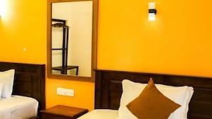 A hotel room with a bed, a nightstand, a mirror, and a wall-mounted light. - Heavens Gate Ella (Ella)