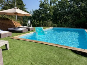 A swimming pool with a wooden deck, lounge chairs, and a sun umbrella. - Country house for nature lovers 15 minutes from the beach (La Garde-Freinet)