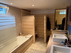 Een moderne badkamer met een douchecabine van hout, een bad, een wastafel en een spiegel.