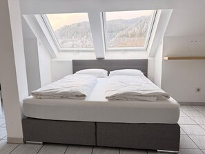 A modern bedroom with a skylight, a bed with white linens, and a view of a snowy landscape. - Faraway Homes Studio Semmering #402 (Spital am Semmering)