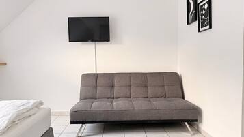 Una camera moderna con un divano, una TV a schermo piatto e due opere d'arte incorniciate al muro.