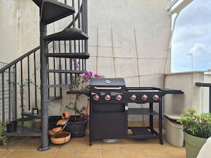 Un barbecue doté d’un panneau de commande, d’un escalier en colimaçon et de plantes en pot.