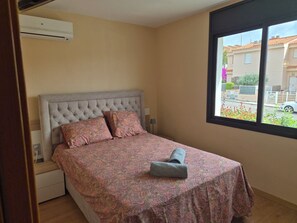 A bedroom with a bed, a window, and an air conditioning unit.
