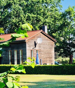 A wooden house with a red roof, a satellite dish, and a blue umbrella. - Vrbo Property (Fuhlendorf)