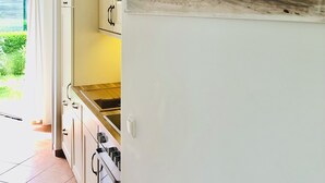 A kitchen with cabinets, a sink, and a painting of tall grasses. - Welcome to the vacation home "OstseeFreiheit", in the Fischland-Darß-Zingst region. (Fuhlendorf)
