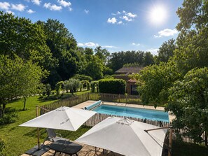 A backyard with a swimming pool, surrounded by lush greenery and a wooden fence. - At Domaine du Pape (Mazères)