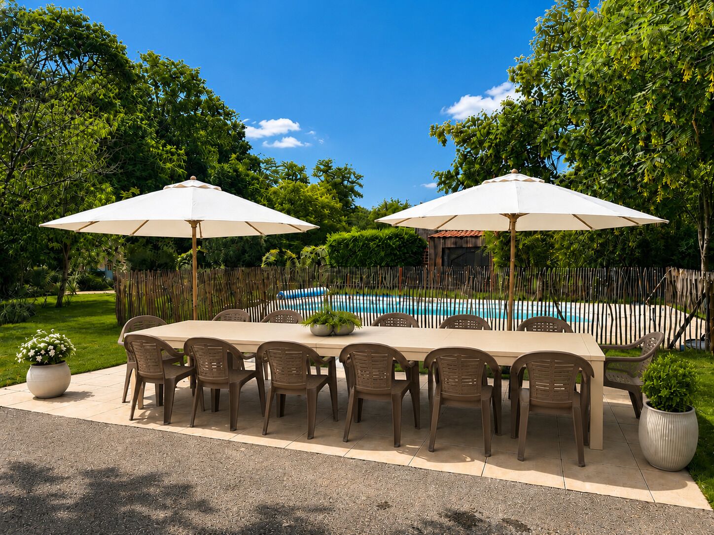 An outdoor dining area with a pool, surrounded by a wooden fence and lush greenery.