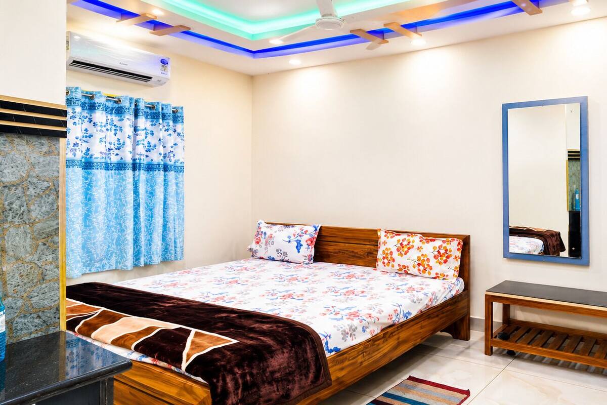 A bedroom with a bed, a wooden bench, a mirror, and a television.