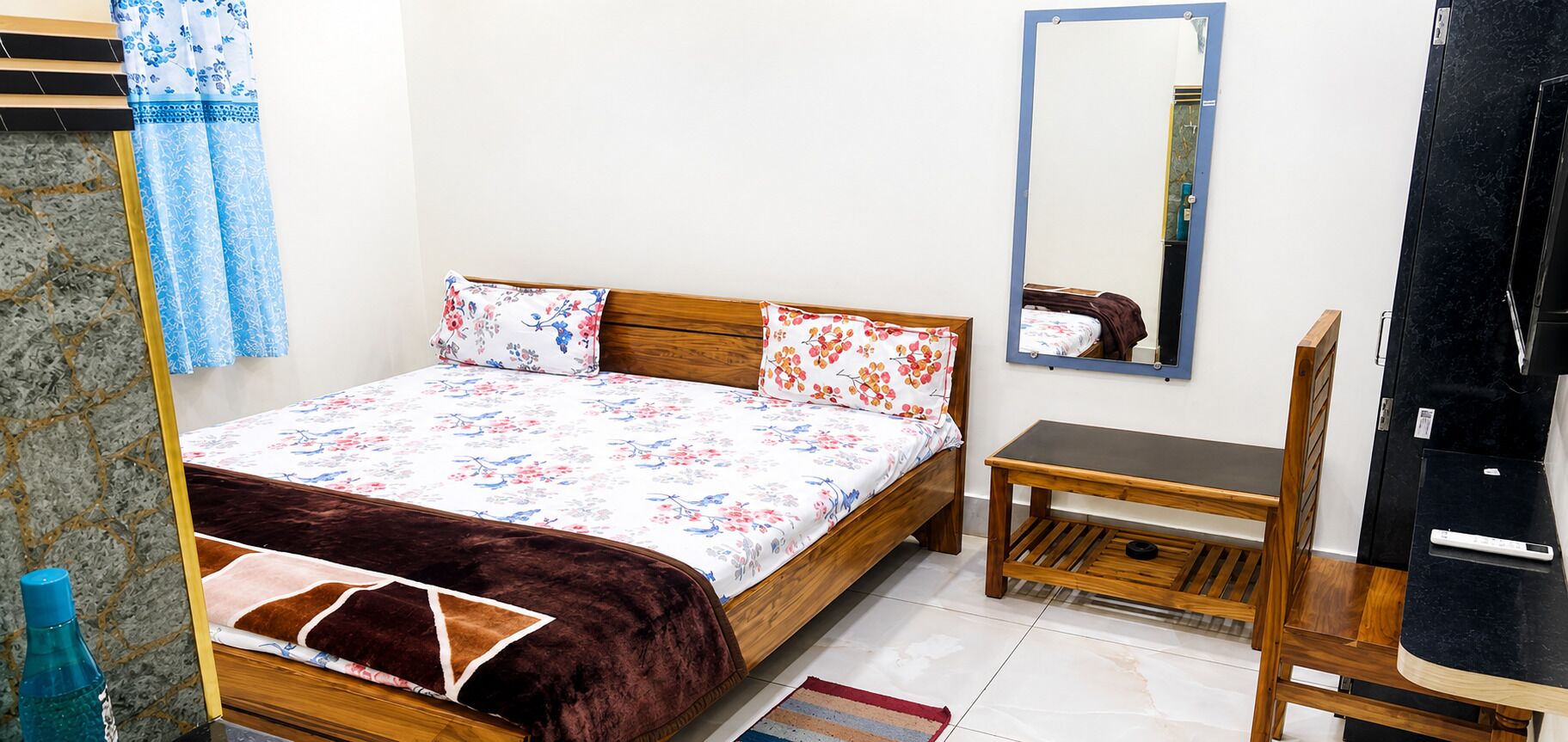 Quarto com cama, mesa de cabeceira, espelho e guarda-roupa.