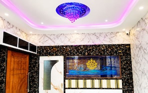 A room with a wooden door, a large abstract artwork, a chandelier, and a marble-patterned wall. - Hotel Niladri Palace - near Sea Beach (Puri)