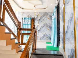 A staircase with wooden railings, marble walls, and a green mat at the bottom. - Hotel Niladri Palace - near Sea Beach (Puri)