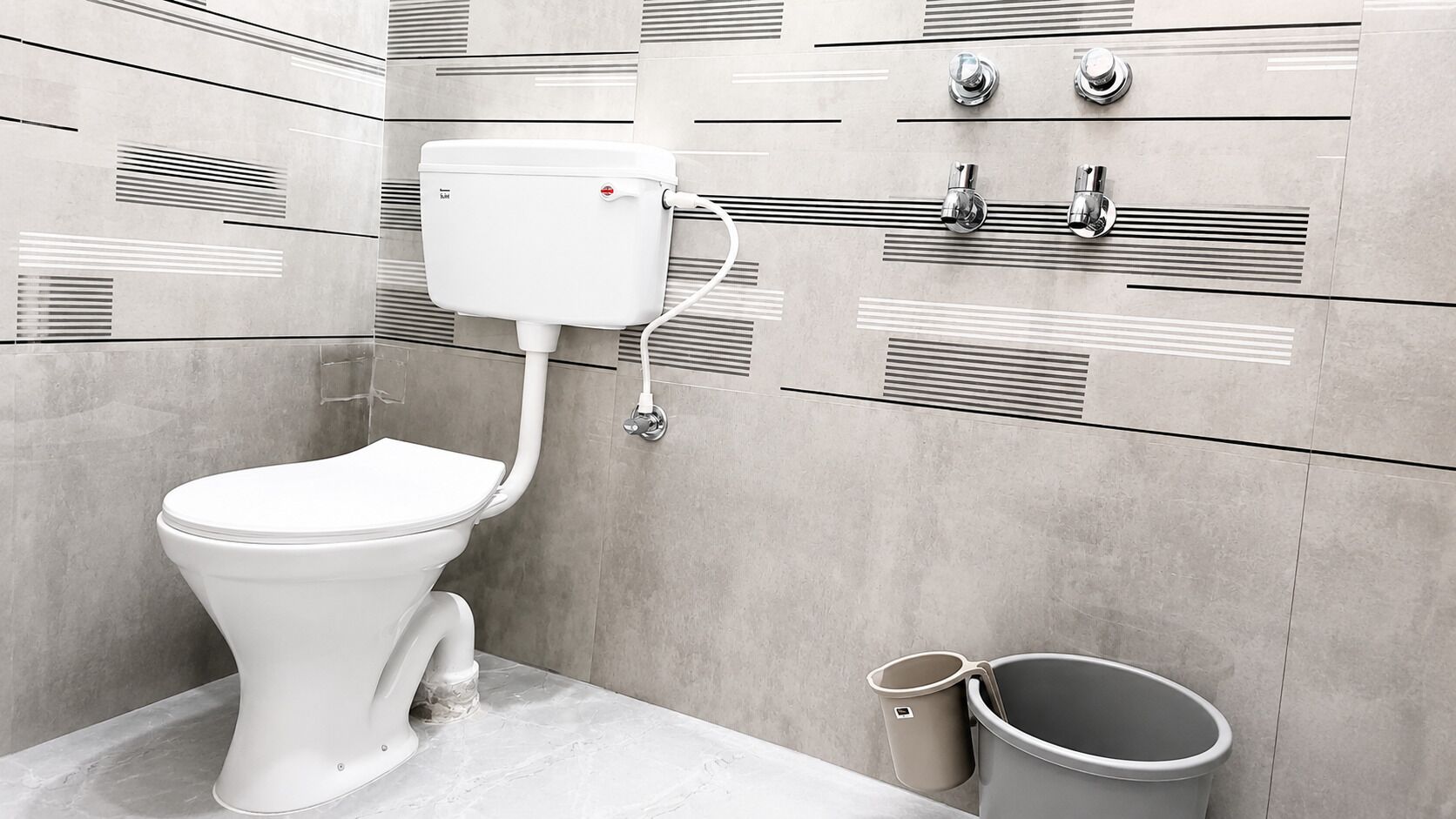 A modern bathroom with a toilet, bidet, and trash can.